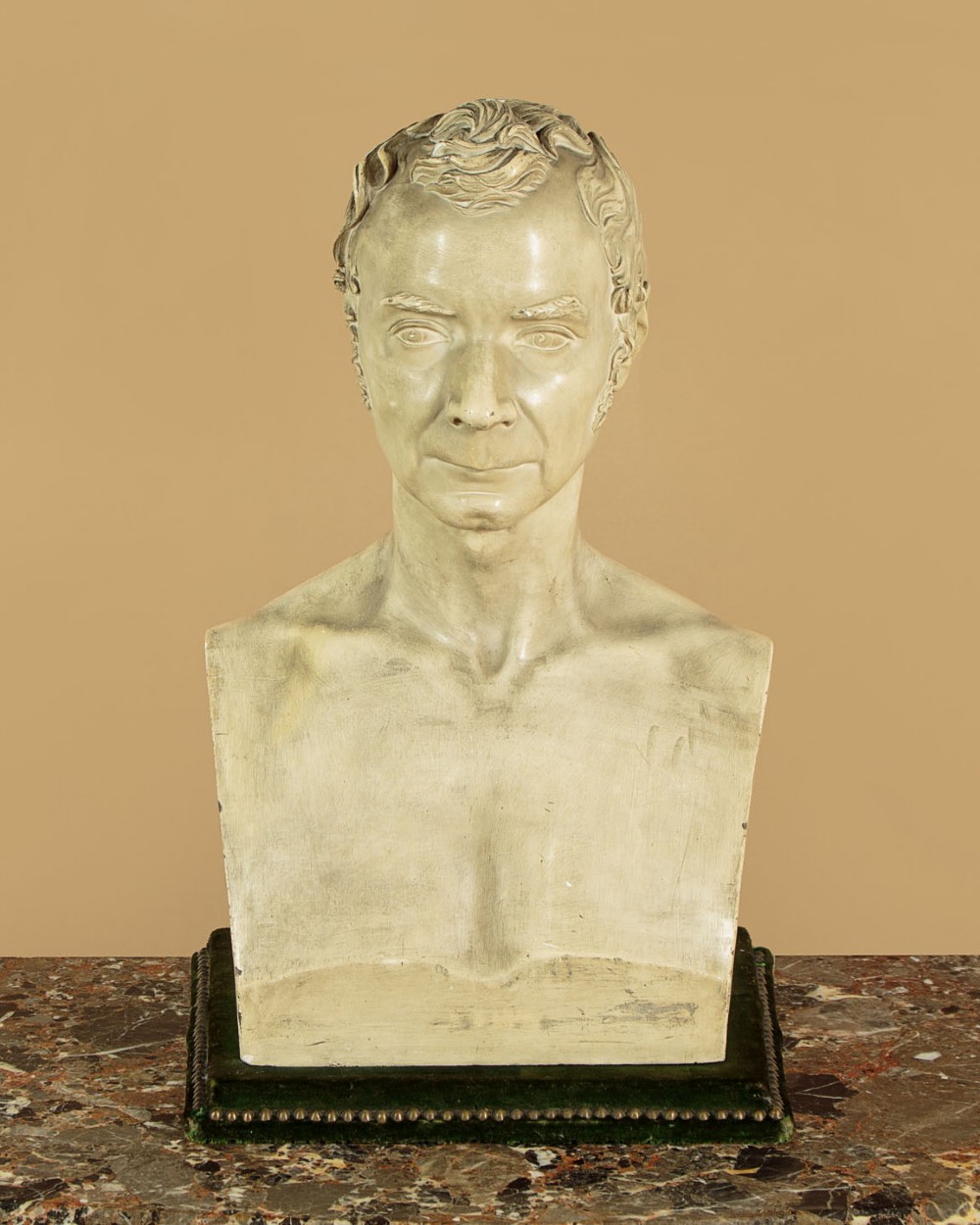 An off-white mid-nineteenth-century plaster bust depicting a gentleman with short wavy hair and bare shoulders.