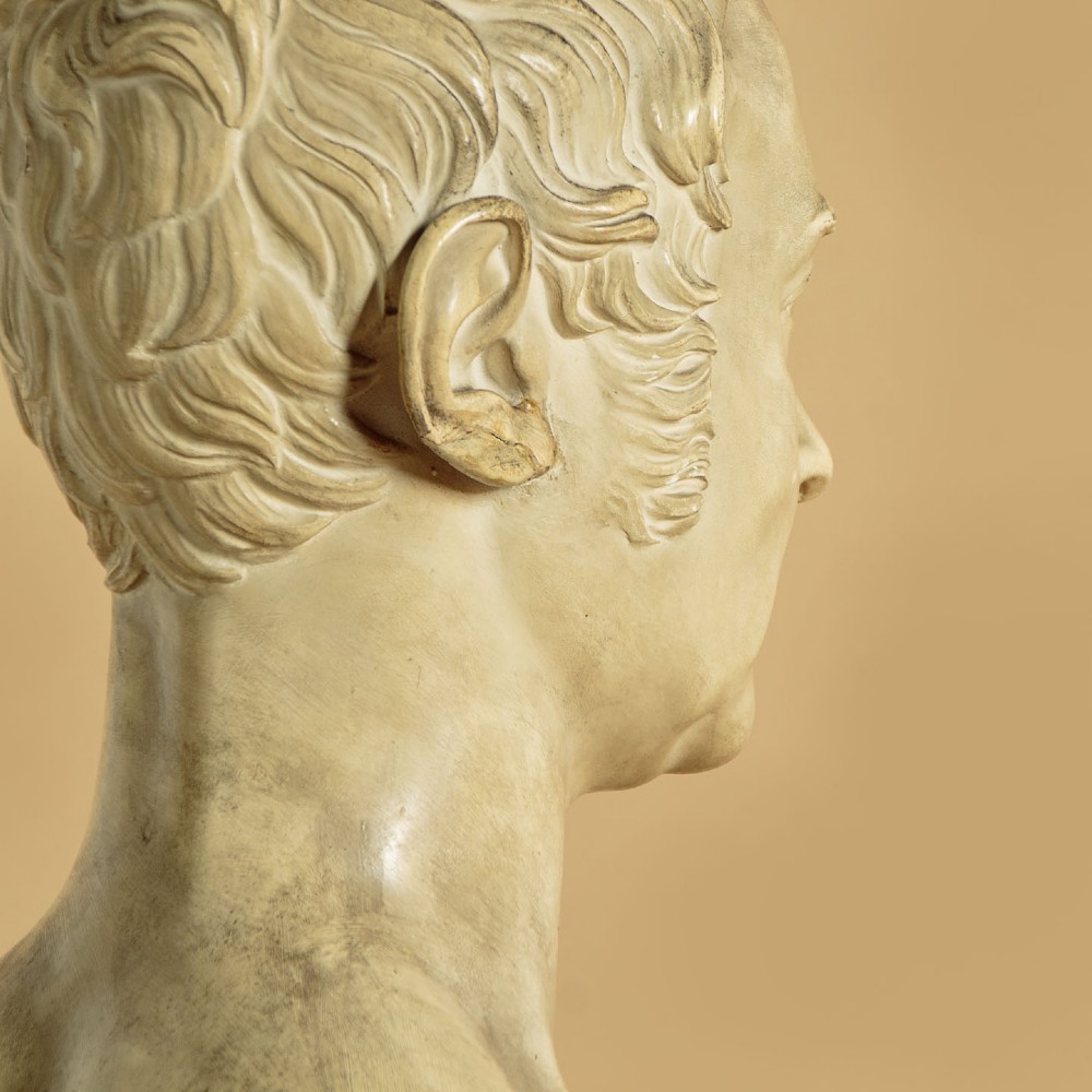 An off-white mid-nineteenth-century plaster bust depicting a gentleman with short wavy hair and bare shoulders. View VII
