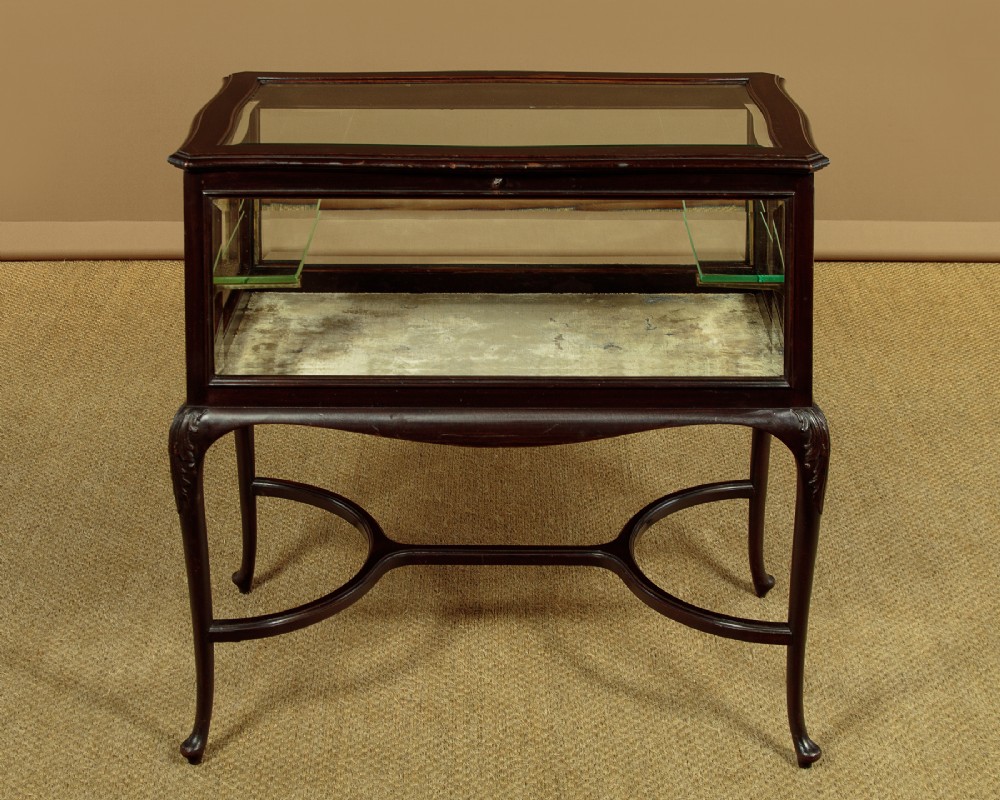 A dark mahogany glass-enclosed bijouterie display table featuring cabriole legs, curved stretchers, glazed side panels, and internal glass shelves. View II