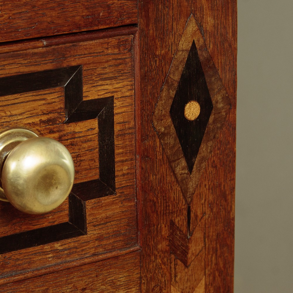 An antique 19th-century Welsh oak bread and cheese cupboard featuring geometric inlaid border details, upper slatted ventilated doors, two drawers, and lower panelled doors on bracket feet. View XII
