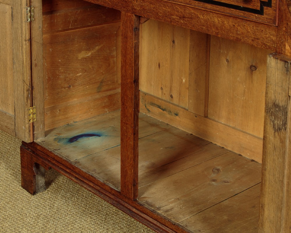 An antique 19th-century Welsh oak bread and cheese cupboard featuring geometric inlaid border details, upper slatted ventilated doors, two drawers, and lower panelled doors on bracket feet. View XV