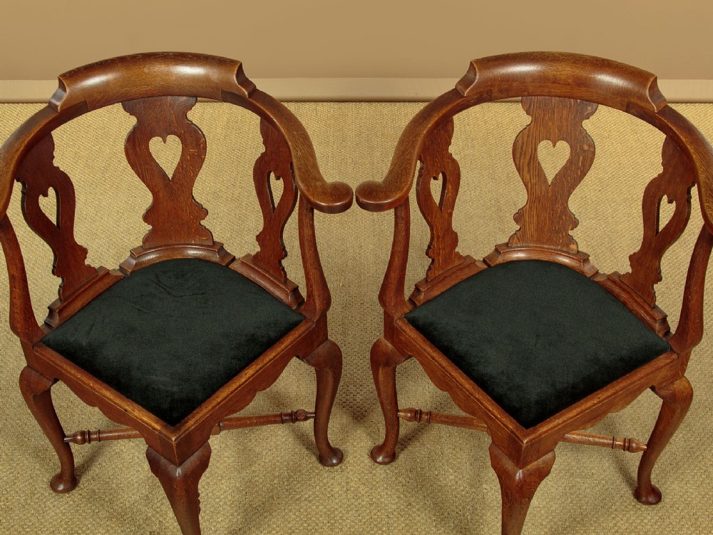 A pair of dark oak corner armchairs featuring pierced heart splats, cabriole legs, turned stretchers, and black upholstered seat cushions. View III