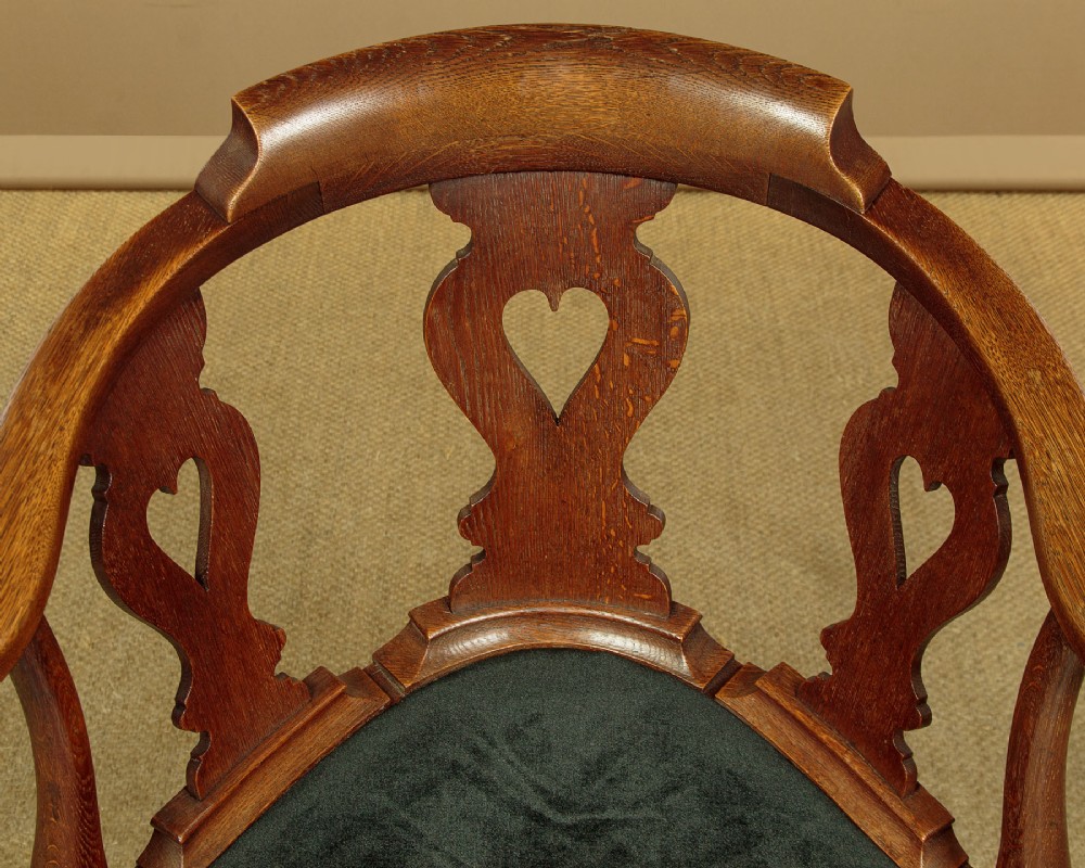 A pair of dark oak corner armchairs featuring pierced heart splats, cabriole legs, turned stretchers, and black upholstered seat cushions. View IV