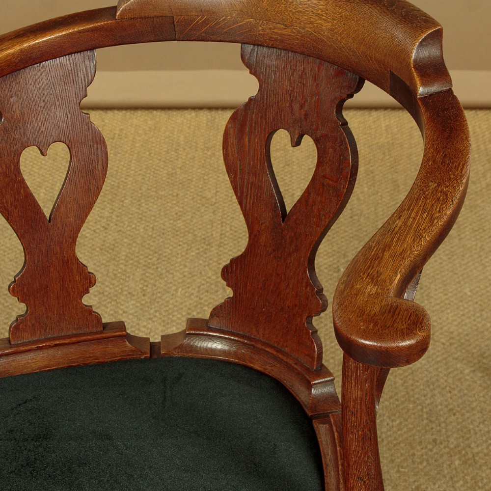 A pair of dark oak corner armchairs featuring pierced heart splats, cabriole legs, turned stretchers, and black upholstered seat cushions. View VI