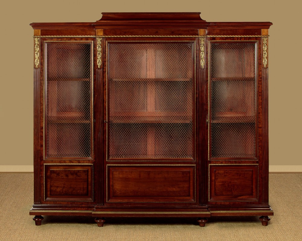 A large Edwardian mahogany breakfront bookcase featuring three sections with brass mesh doors, decorative brass mounts, and a central projecting stepped section.