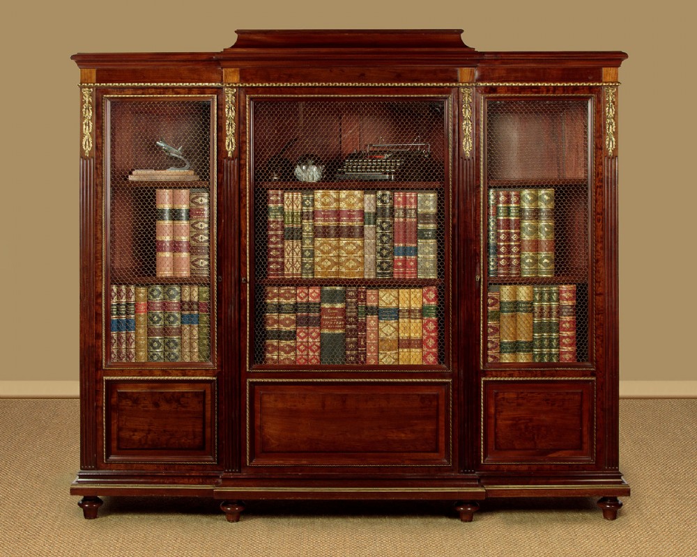 A large Edwardian mahogany breakfront bookcase featuring three sections with brass mesh doors, decorative brass mounts, and a central projecting stepped section. View II