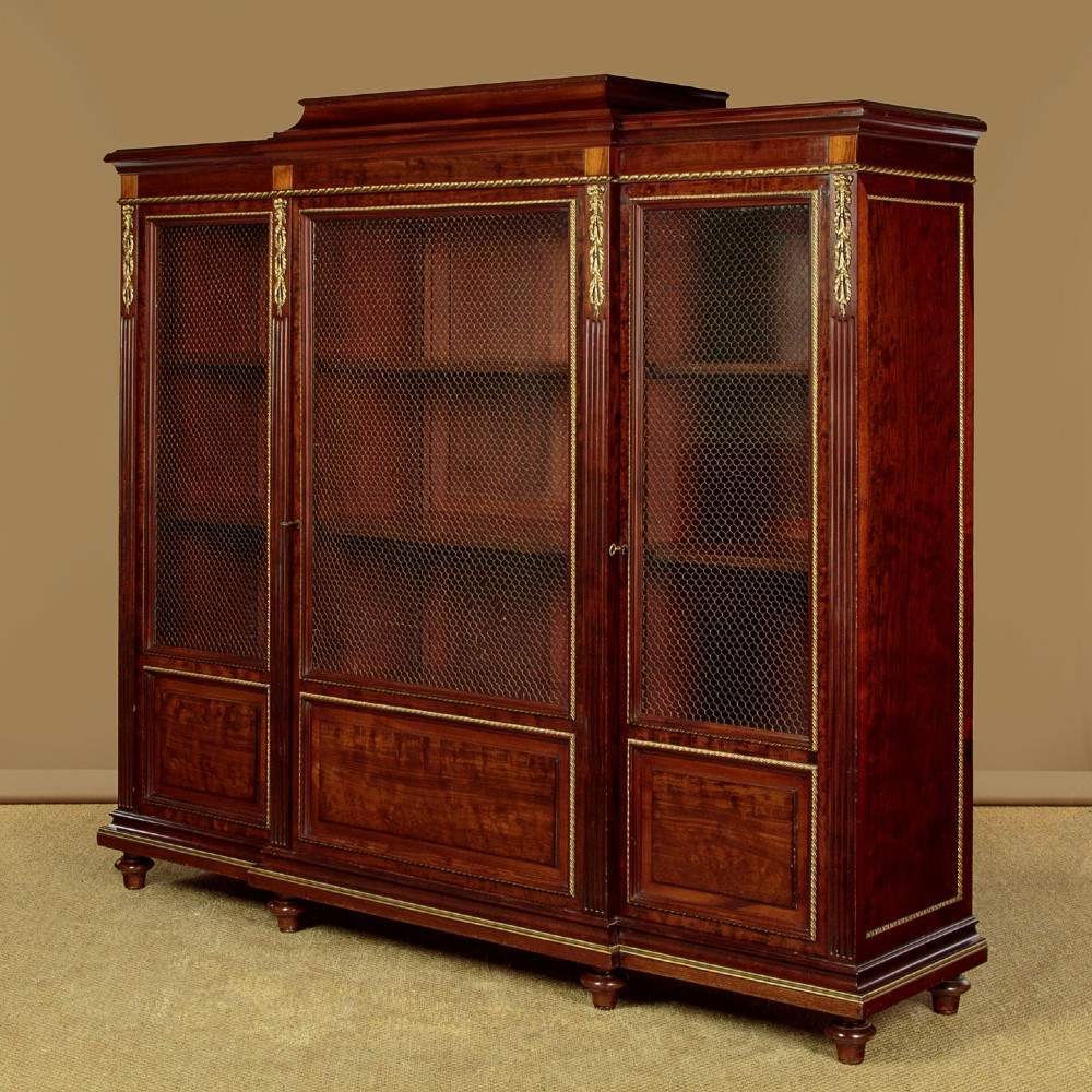 A large Edwardian mahogany breakfront bookcase featuring three sections with brass mesh doors, decorative brass mounts, and a central projecting stepped section. View III
