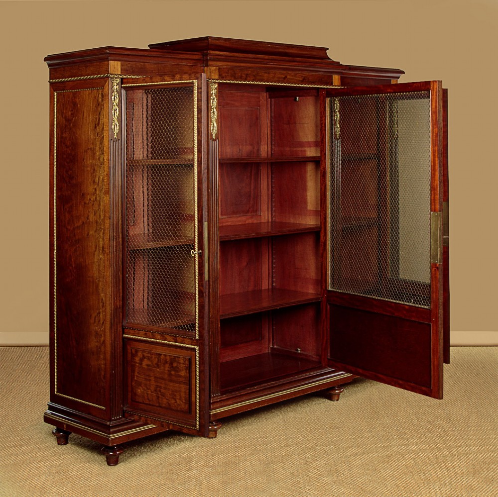 A large Edwardian mahogany breakfront bookcase featuring three sections with brass mesh doors, decorative brass mounts, and a central projecting stepped section. View IV