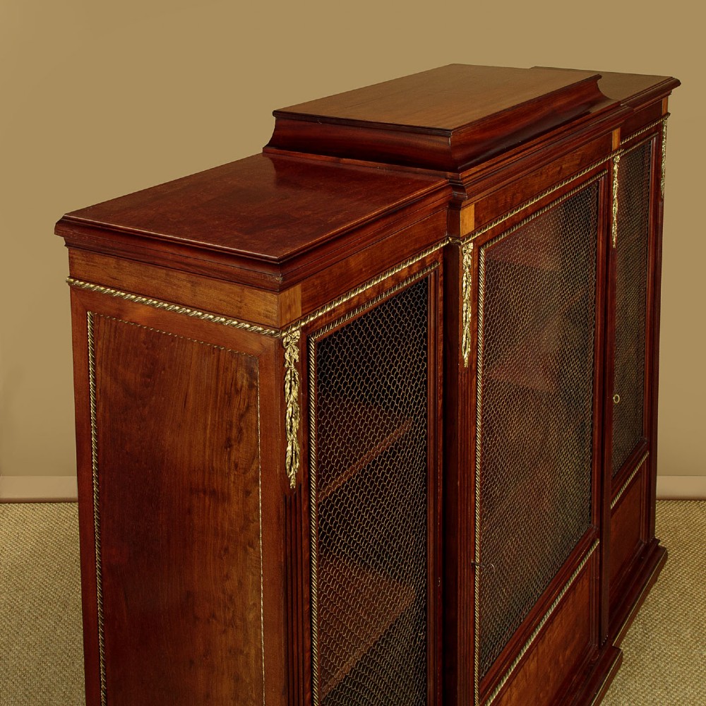A large Edwardian mahogany breakfront bookcase featuring three sections with brass mesh doors, decorative brass mounts, and a central projecting stepped section. View V