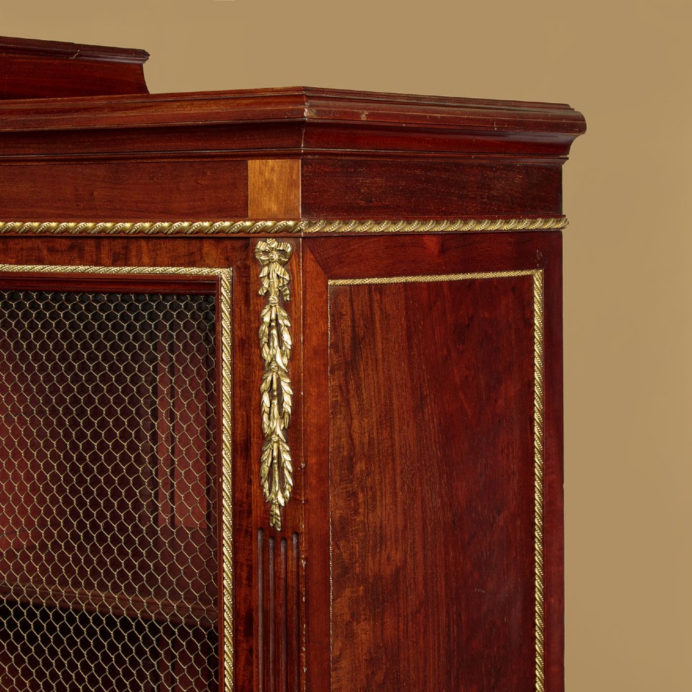 A large Edwardian mahogany breakfront bookcase featuring three sections with brass mesh doors, decorative brass mounts, and a central projecting stepped section. View VI