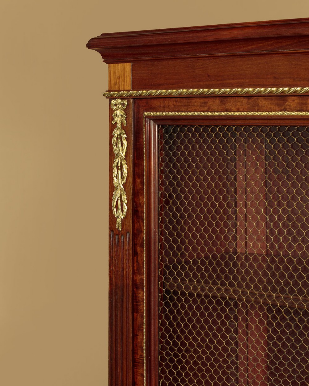 A large Edwardian mahogany breakfront bookcase featuring three sections with brass mesh doors, decorative brass mounts, and a central projecting stepped section. View VII