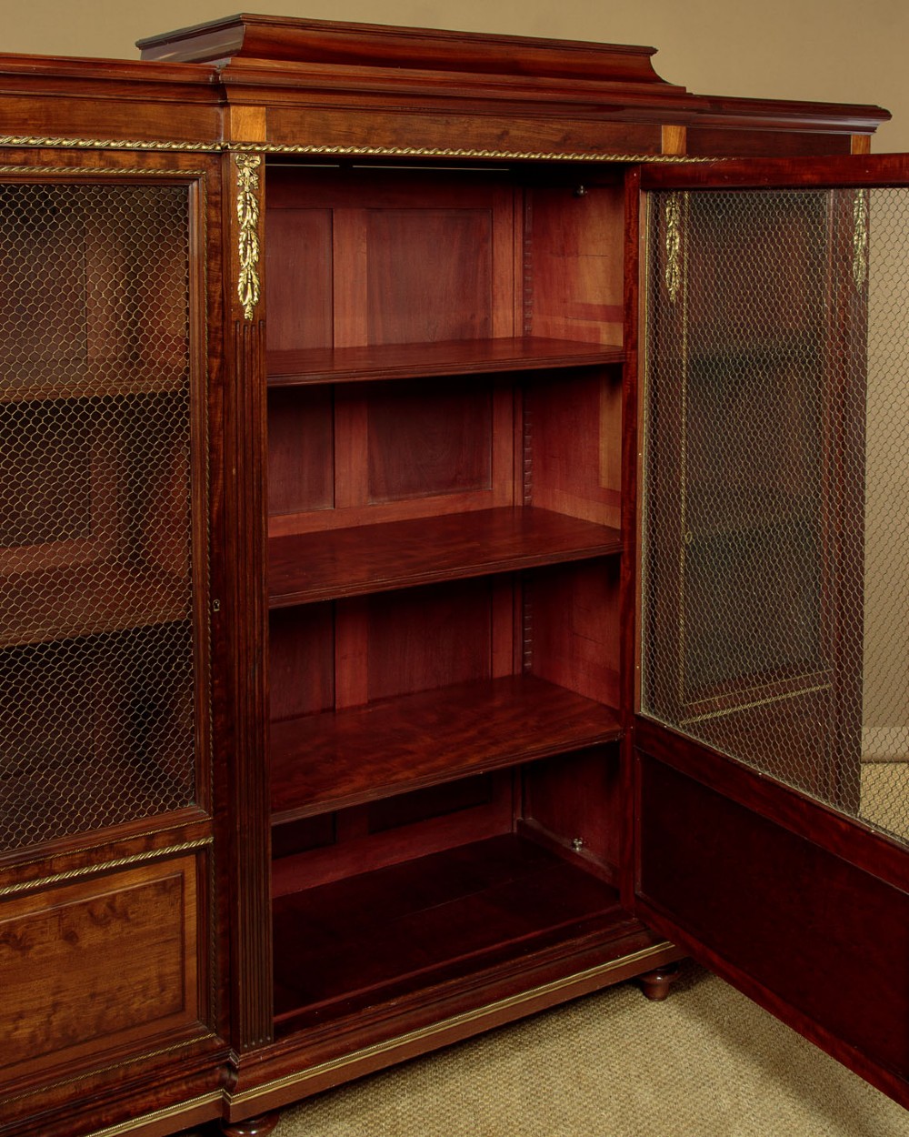 A large Edwardian mahogany breakfront bookcase featuring three sections with brass mesh doors, decorative brass mounts, and a central projecting stepped section. View VIII