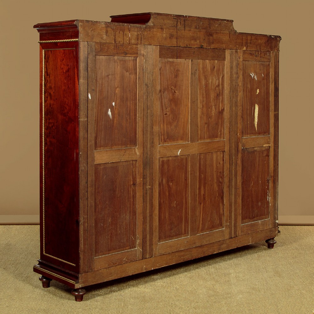 A large Edwardian mahogany breakfront bookcase featuring three sections with brass mesh doors, decorative brass mounts, and a central projecting stepped section. View XI