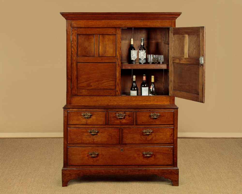 An antique two-part Welsh oak cupboard featuring a double door top section with fielded panels above a chest with six drawers on bracket feet. View II