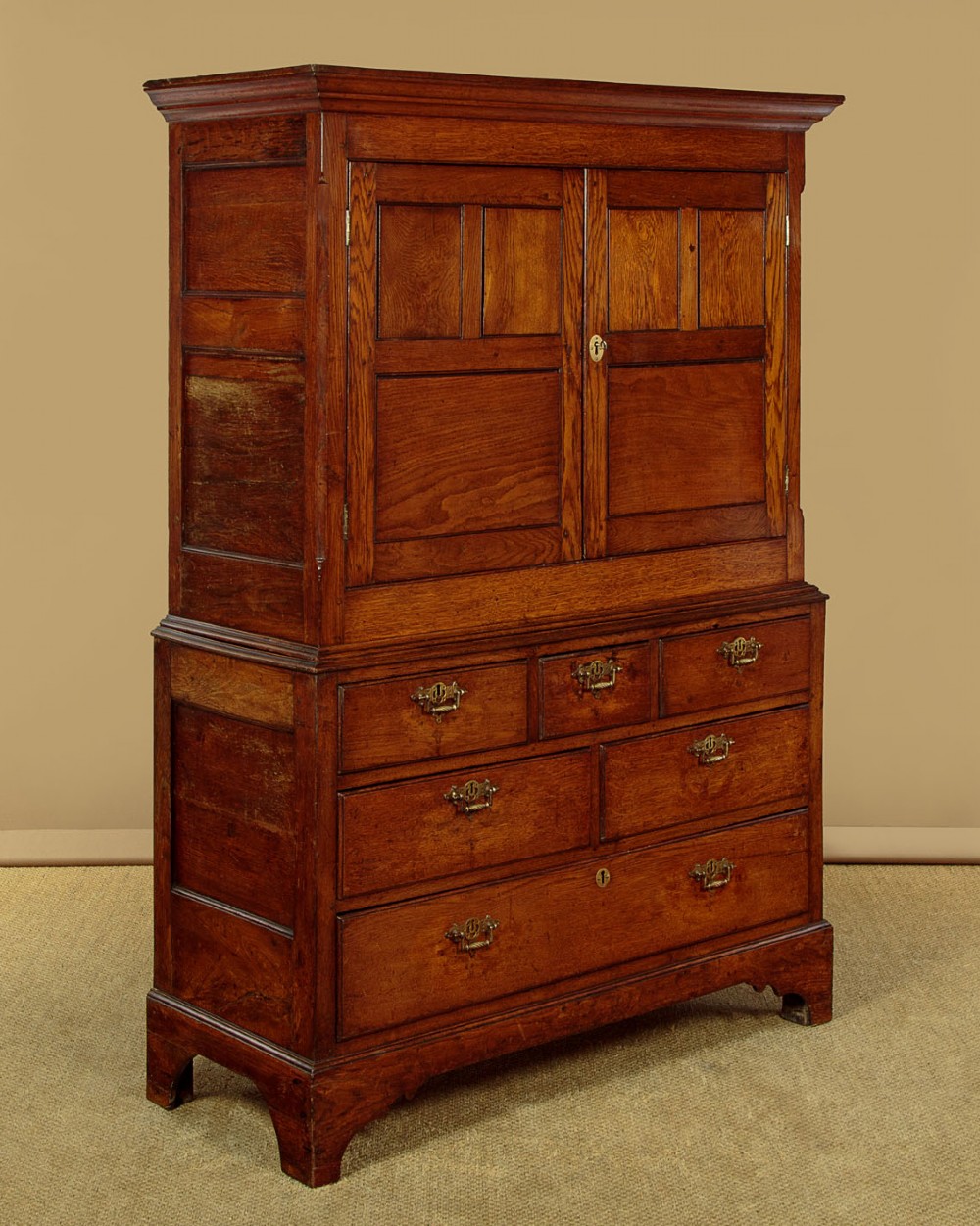 An antique two-part Welsh oak cupboard featuring a double door top section with fielded panels above a chest with six drawers on bracket feet. View III