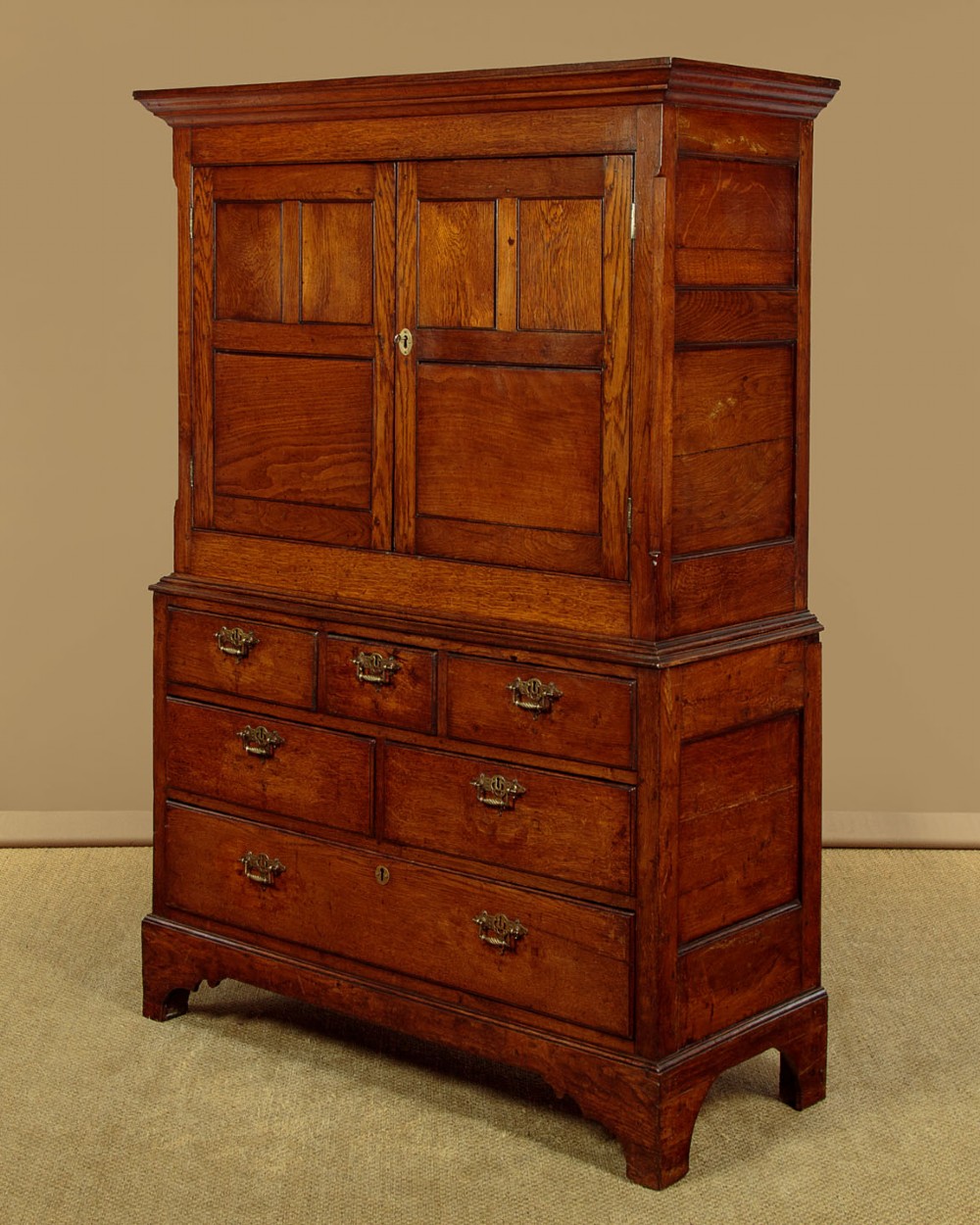 An antique two-part Welsh oak cupboard featuring a double door top section with fielded panels above a chest with six drawers on bracket feet. View IV