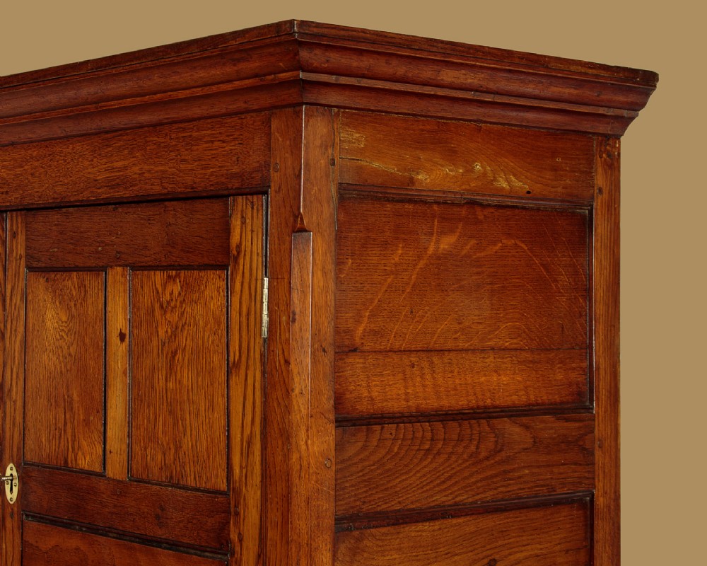 An antique two-part Welsh oak cupboard featuring a double door top section with fielded panels above a chest with six drawers on bracket feet. View VI