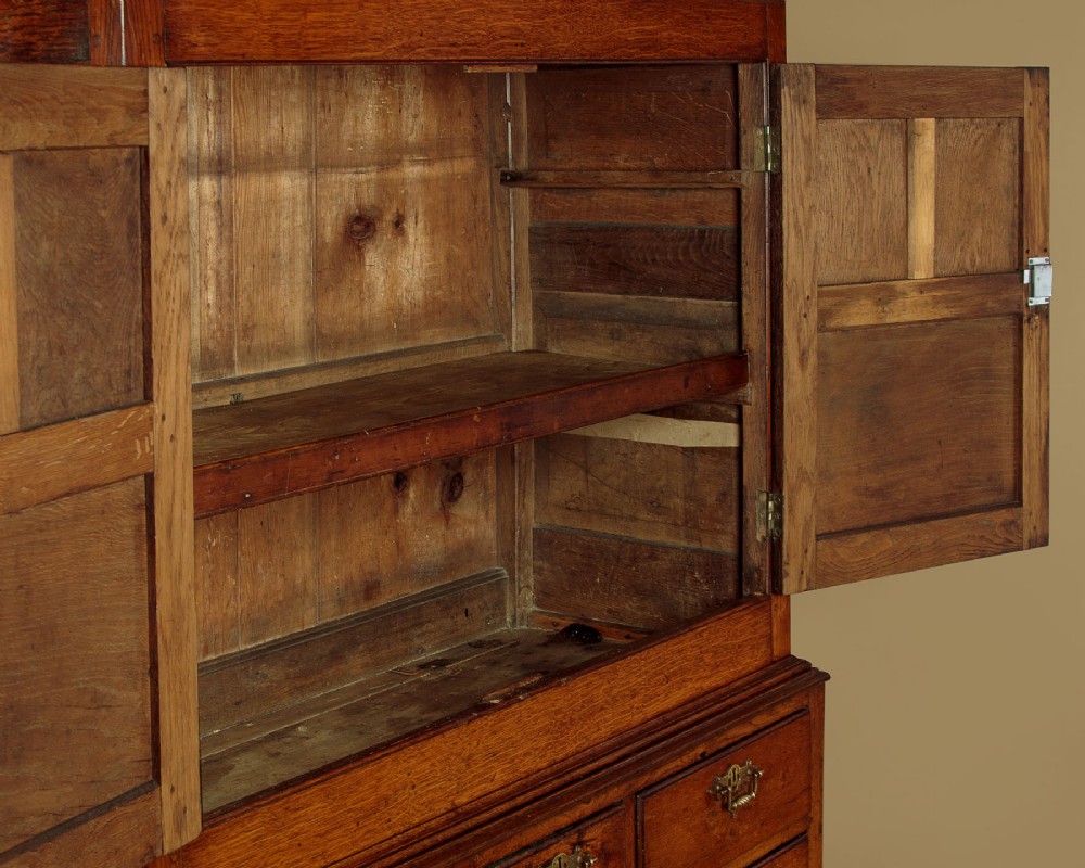 An antique two-part Welsh oak cupboard featuring a double door top section with fielded panels above a chest with six drawers on bracket feet. View VII