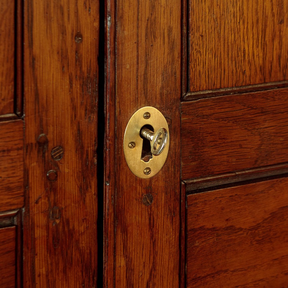An antique two-part Welsh oak cupboard featuring a double door top section with fielded panels above a chest with six drawers on bracket feet. View VIII