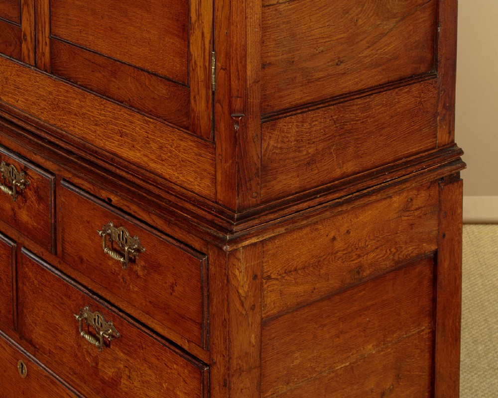 An antique two-part Welsh oak cupboard featuring a double door top section with fielded panels above a chest with six drawers on bracket feet. View IX
