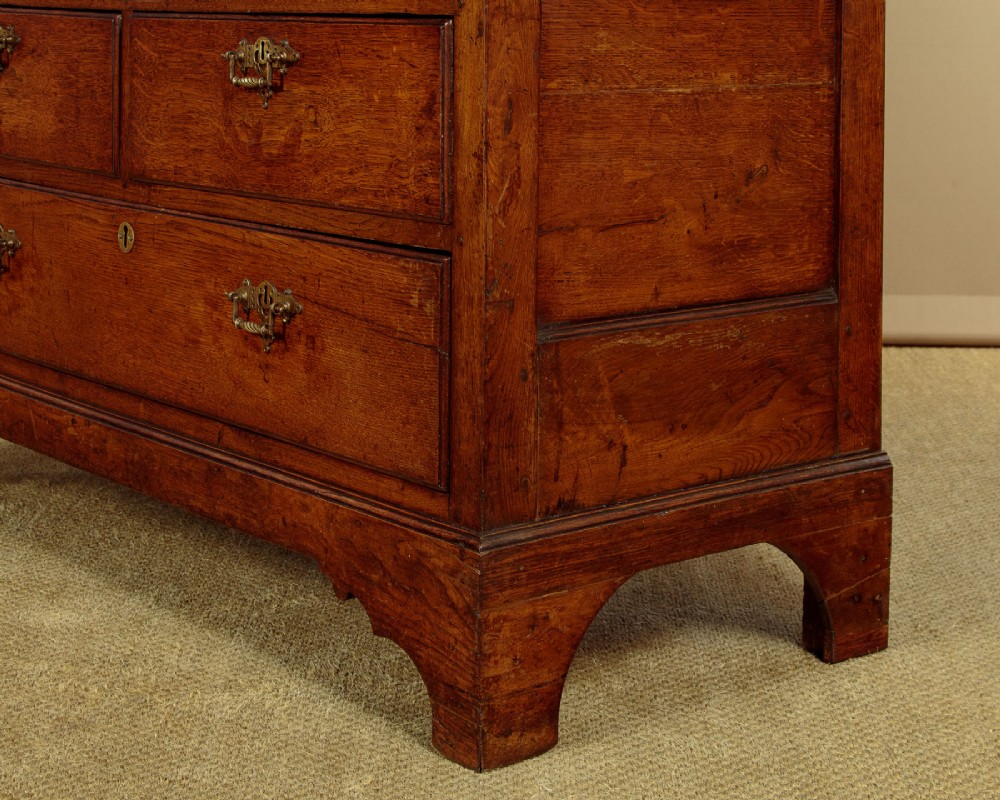An antique two-part Welsh oak cupboard featuring a double door top section with fielded panels above a chest with six drawers on bracket feet. View X