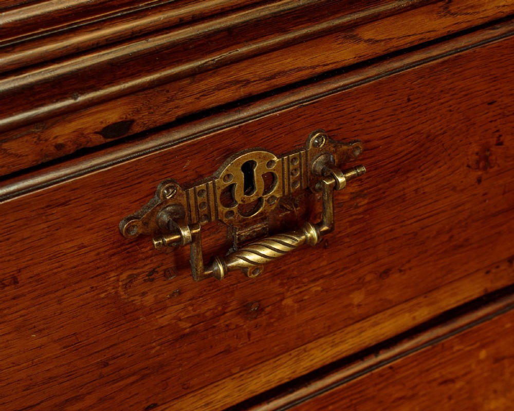 An antique two-part Welsh oak cupboard featuring a double door top section with fielded panels above a chest with six drawers on bracket feet. View XII