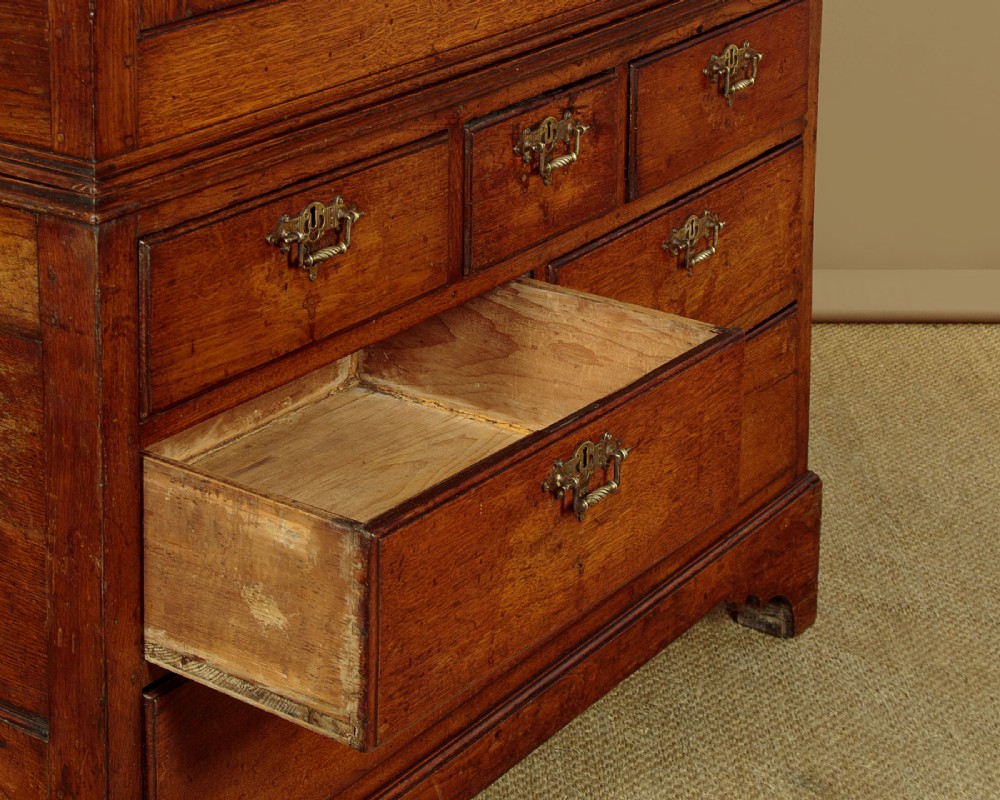 An antique two-part Welsh oak cupboard featuring a double door top section with fielded panels above a chest with six drawers on bracket feet. View XIII