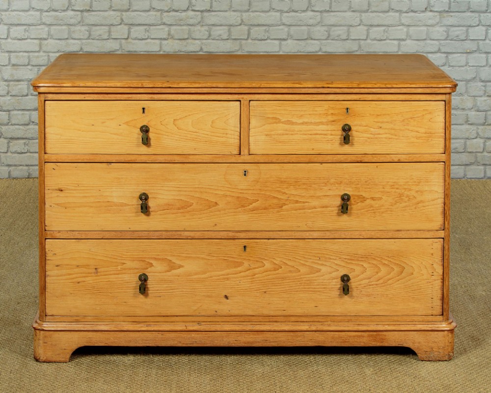 A late Victorian natural pine chest of drawers featuring a two short over two long drawer layout with brass drop handles.