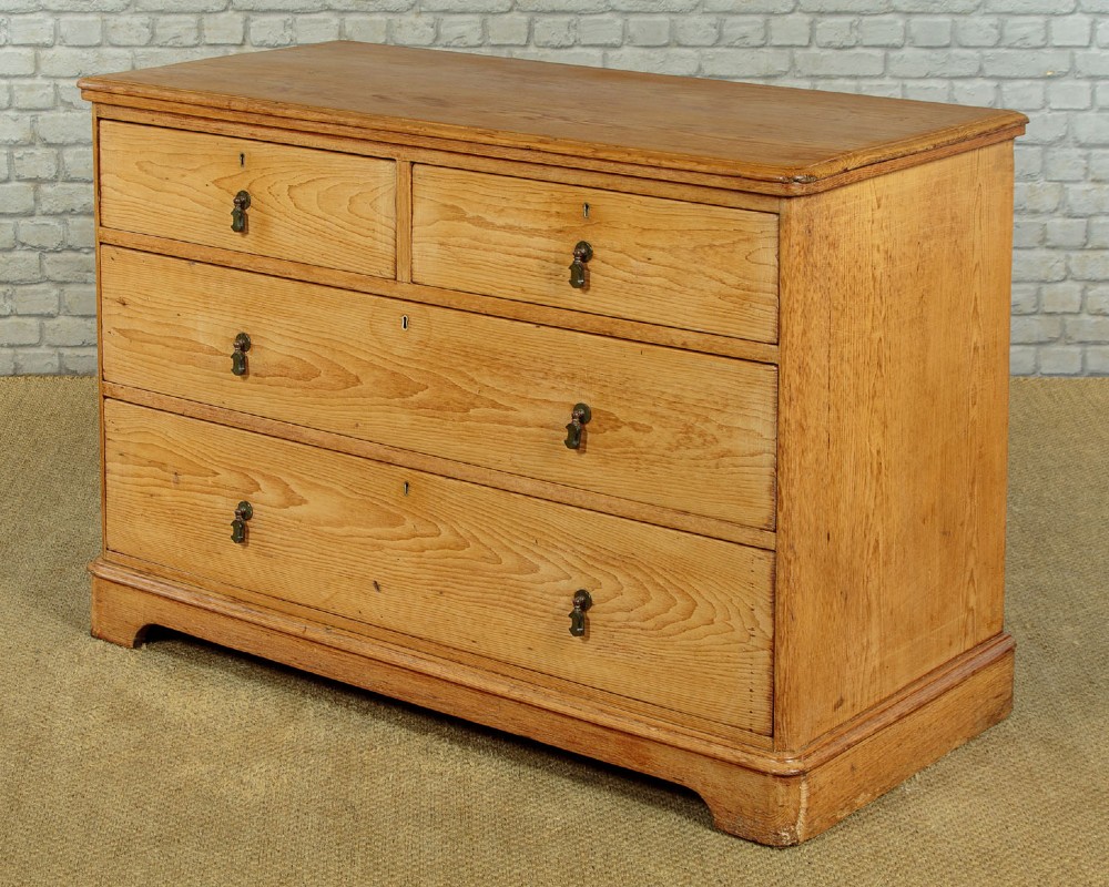 A late Victorian natural pine chest of drawers featuring a two short over two long drawer layout with brass drop handles. View II