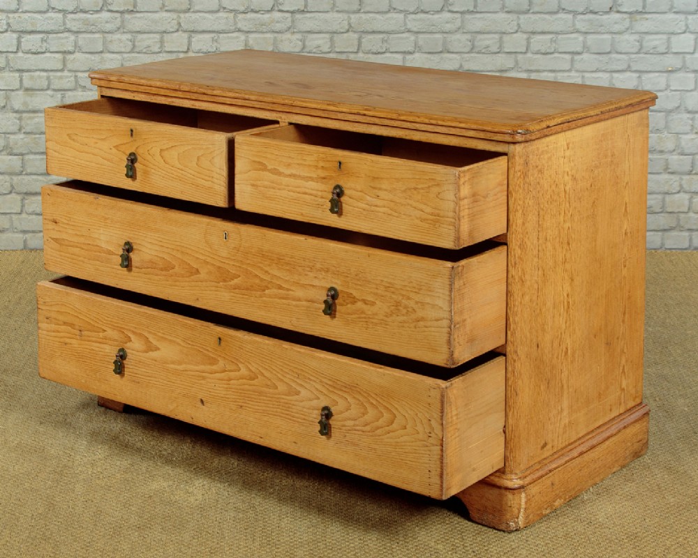 A late Victorian natural pine chest of drawers featuring a two short over two long drawer layout with brass drop handles. View IV