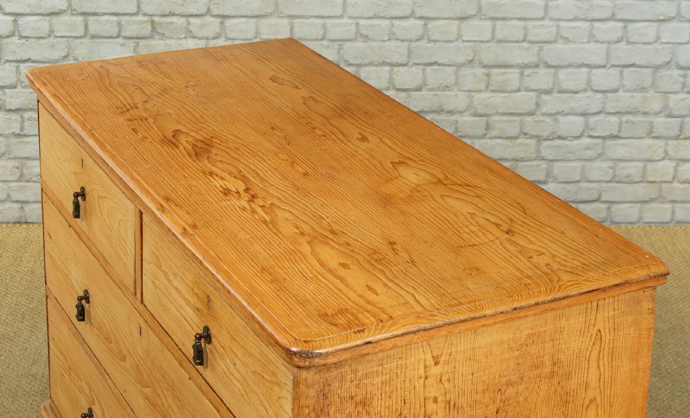 A late Victorian natural pine chest of drawers featuring a two short over two long drawer layout with brass drop handles. View V