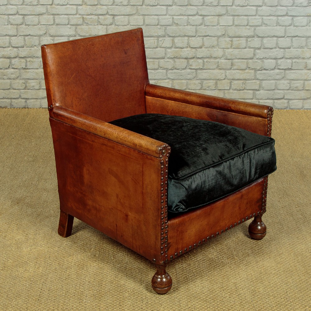 A pair of small 1920s brown leather armchairs featuring brass stud detailing, turned front legs, and dark velvet seat cushions. View III