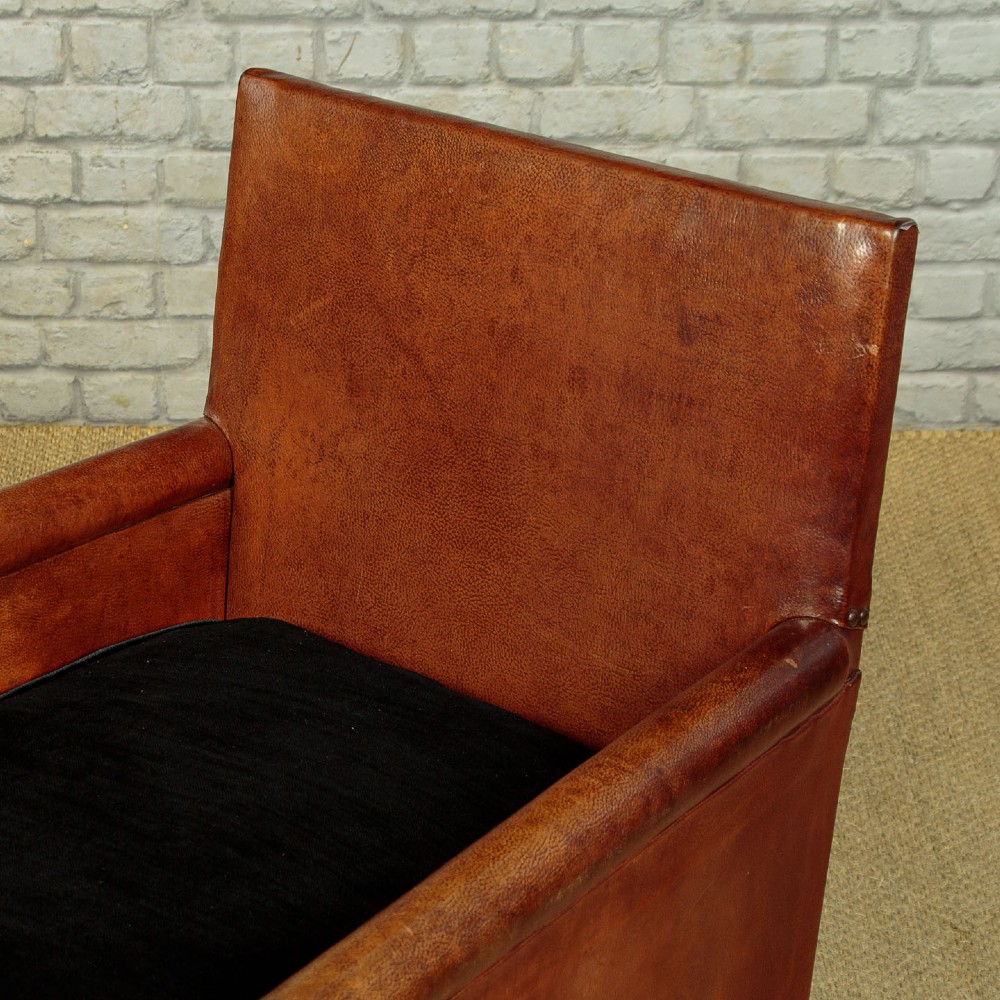 A pair of small 1920s brown leather armchairs featuring brass stud detailing, turned front legs, and dark velvet seat cushions. View VIII