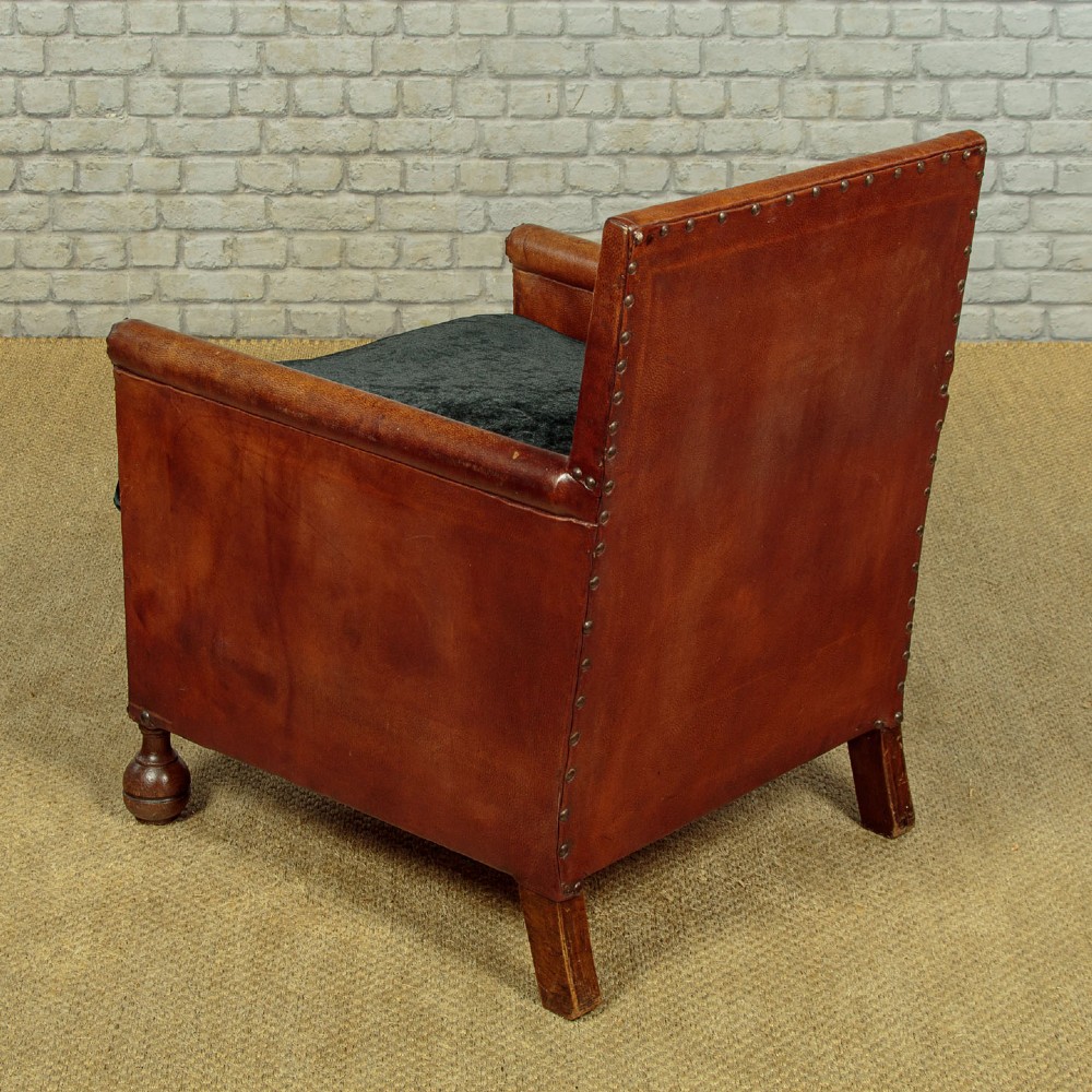A pair of small 1920s brown leather armchairs featuring brass stud detailing, turned front legs, and dark velvet seat cushions. View XIII