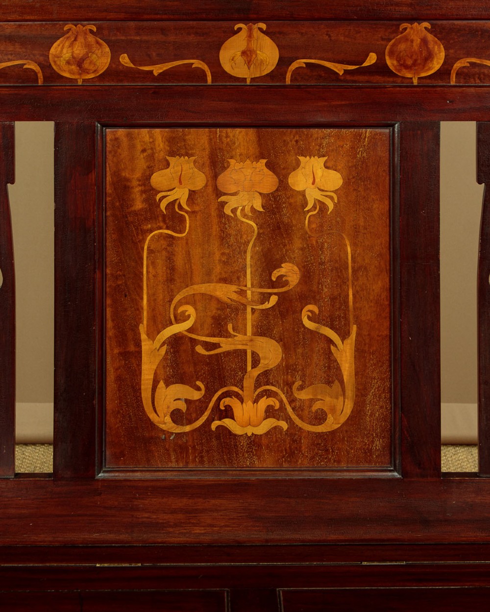 A dark mahogany high-back Arts and Crafts box settle featuring stylised floral marquetry inlay and vertical splat details above a hinged lift-up storage seat. View IV