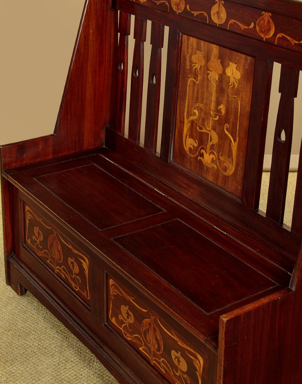 A dark mahogany high-back Arts and Crafts box settle featuring stylised floral marquetry inlay and vertical splat details above a hinged lift-up storage seat. View VII