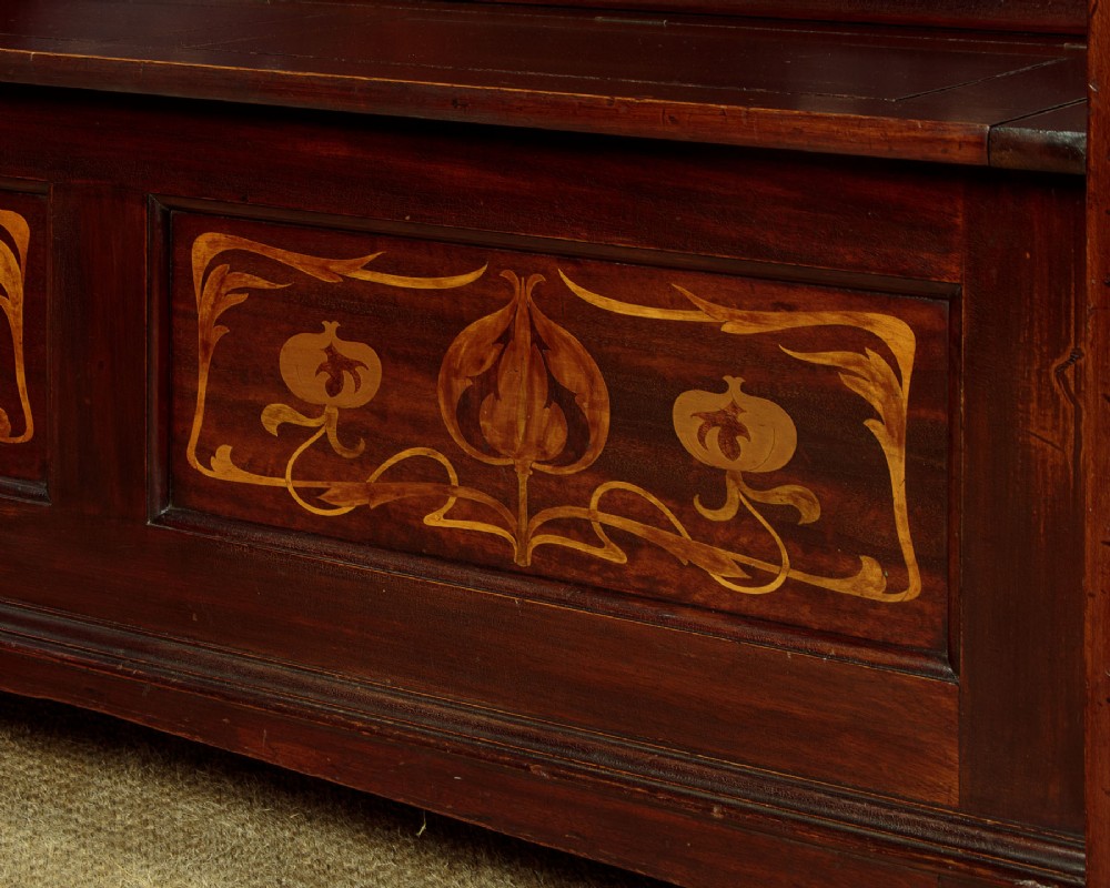 A dark mahogany high-back Arts and Crafts box settle featuring stylised floral marquetry inlay and vertical splat details above a hinged lift-up storage seat. View IX