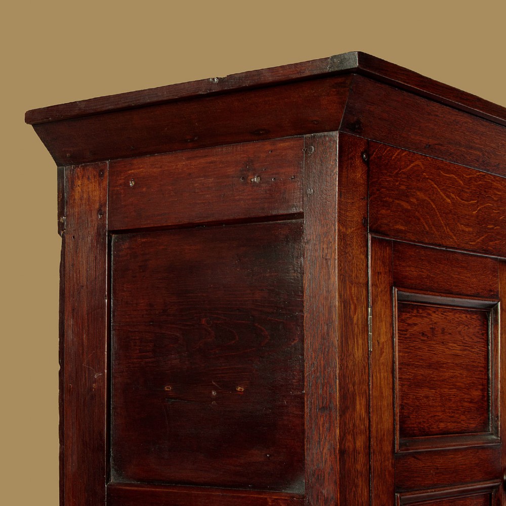 A two-section Georgian Welsh dark oak bread and cheese cupboard featuring upper panelled doors with fretwork ventilation grilles, two drawers, and a double-door lower section. View VI