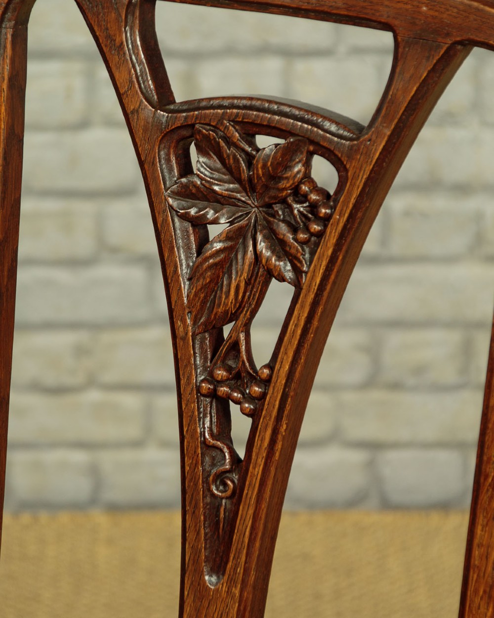A set of six Art Nouveau oak dining chairs featuring carved botanical backrests and dark brown leather seats with brass stud trim. View VII