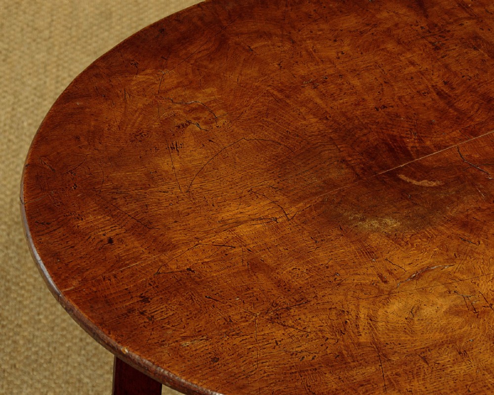 A mid-19th-century pollard oak cricket table with a round top, three splayed legs, and a triangular lower shelf. View V