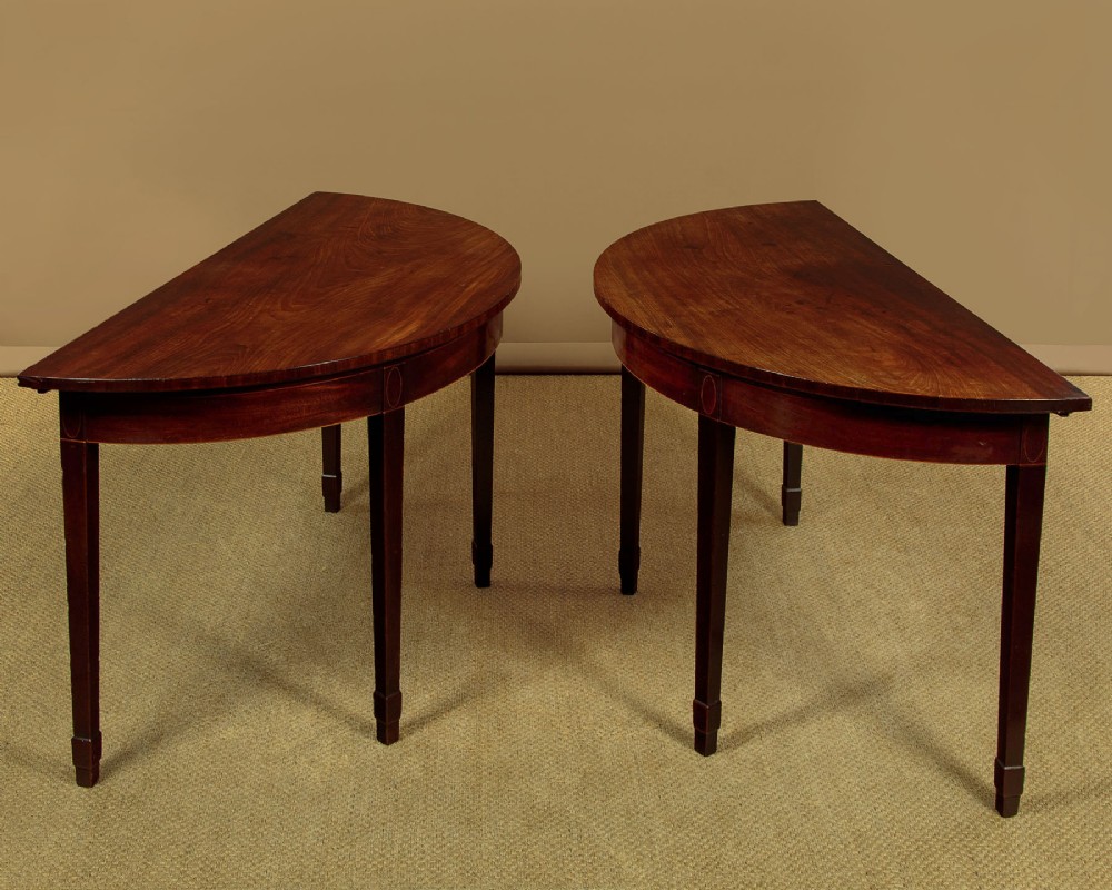 A pair of late George III mahogany demi-lune side tables featuring inlaid aprons and square tapered legs. View III