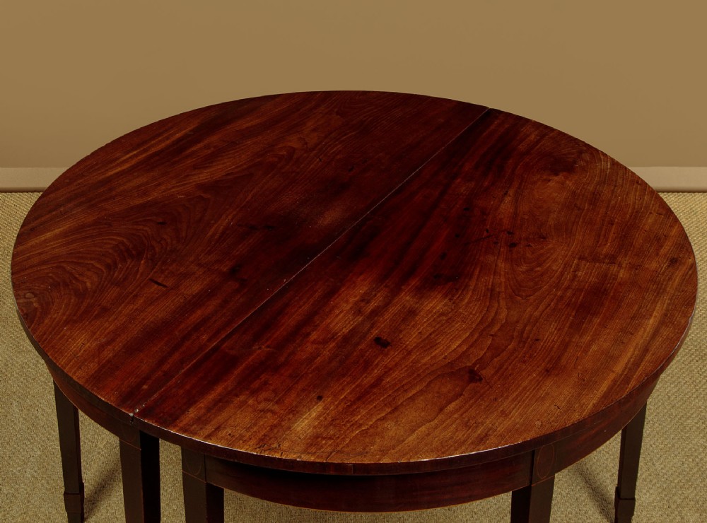 A pair of late George III mahogany demi-lune side tables featuring inlaid aprons and square tapered legs. View V
