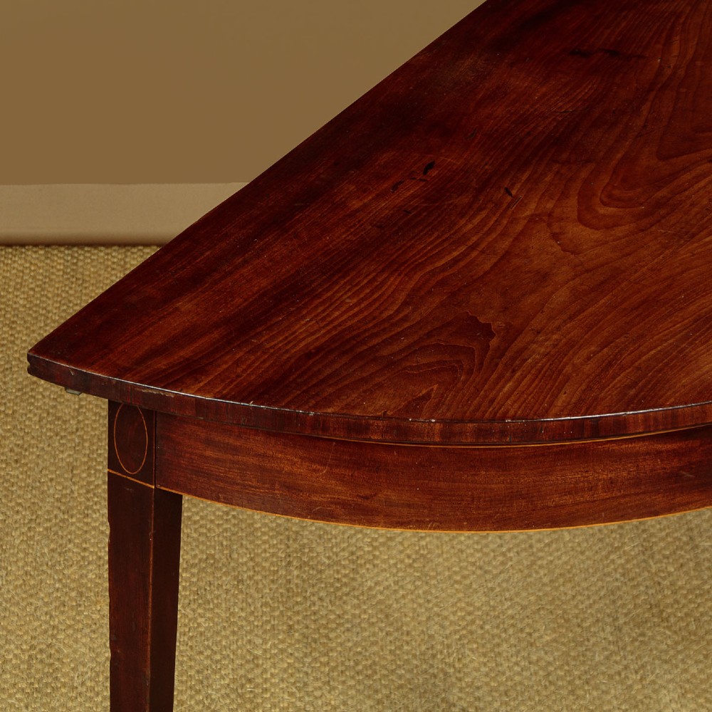 A pair of late George III mahogany demi-lune side tables featuring inlaid aprons and square tapered legs. View VI