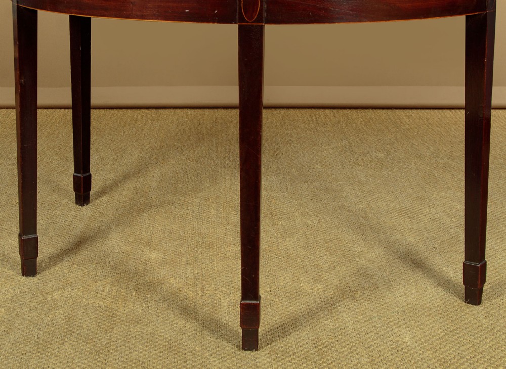 A pair of late George III mahogany demi-lune side tables featuring inlaid aprons and square tapered legs. View IX