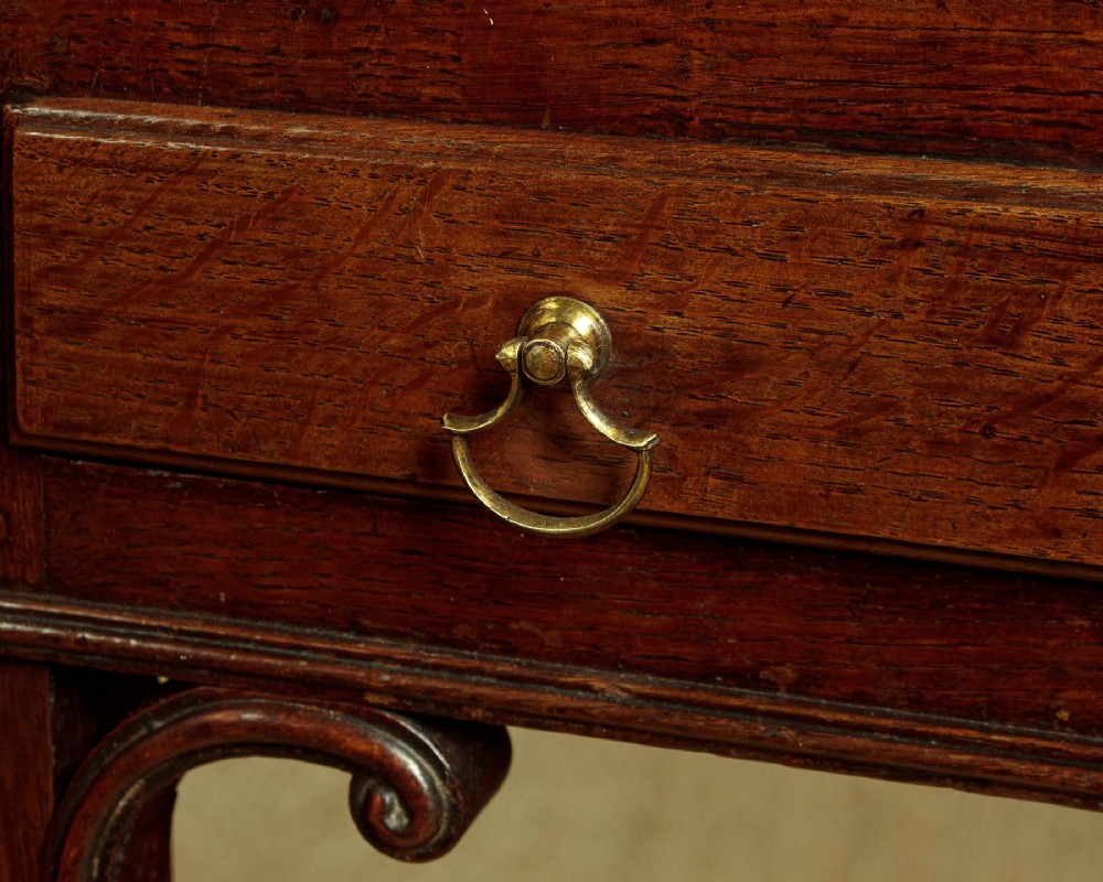 A George III dark oak potboard dresser base featuring three upper drawers, four frieze drawers, brass handles, shaped spandrels, and a low open shelf. View XII