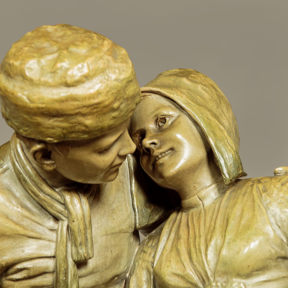 A patinated terracotta sculpture depicting a man and woman in traditional rural attire embracing while holding a woven basket. View V