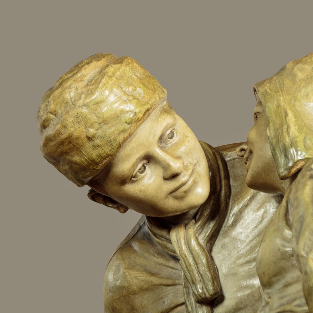 A patinated terracotta sculpture depicting a man and woman in traditional rural attire embracing while holding a woven basket. View VI