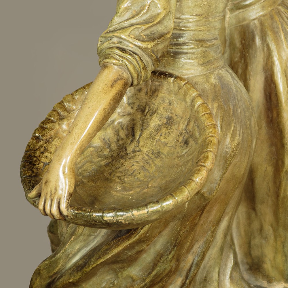 A patinated terracotta sculpture depicting a man and woman in traditional rural attire embracing while holding a woven basket. View VIII