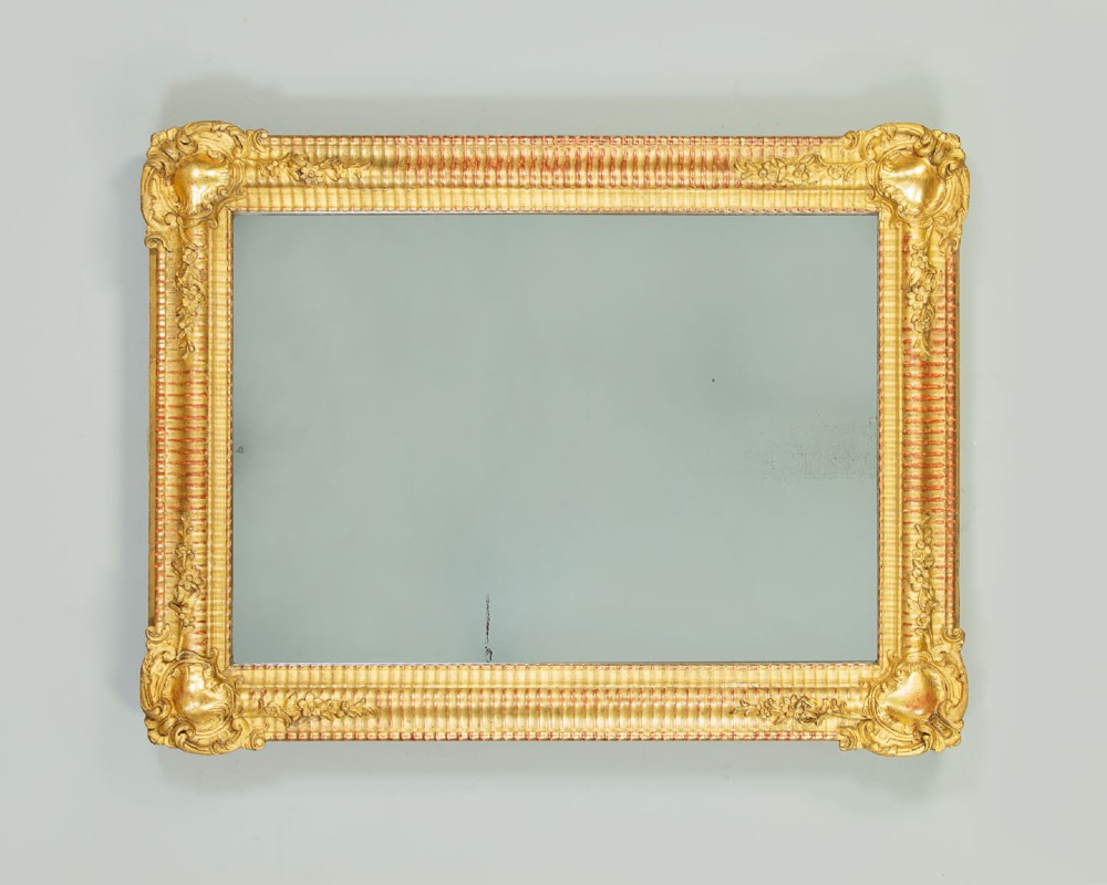 A late 19th-century rectangular French giltwood wall mirror featuring carved corner cartouches, gadrooned borders, and visible red bole beneath gold leaf. View III