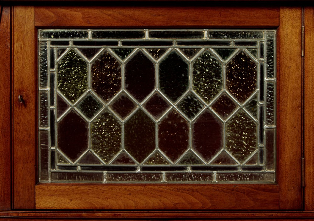 An Arts and Crafts oak side cabinet featuring an upper spindle gallery, arched open shelves, diagonal side struts, and a central cabinet door with leaded glass. View VIII